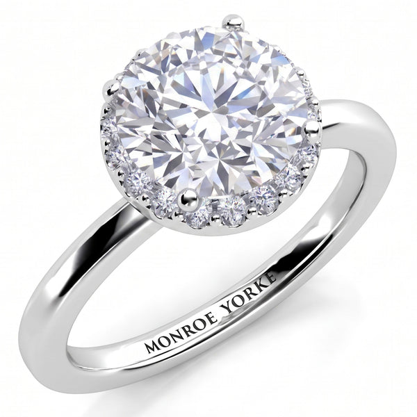 Alexa unique halo engagement ring in white gold or platinum, angled view of the round brilliant centre diamond with the halo set beneath it, Monroe Yorke engraved on the band.