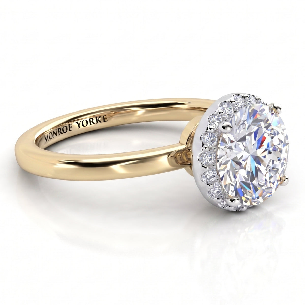 Alexa unique halo engagement ring in yellow gold, low front view of the round centre diamond above a plain polished band.