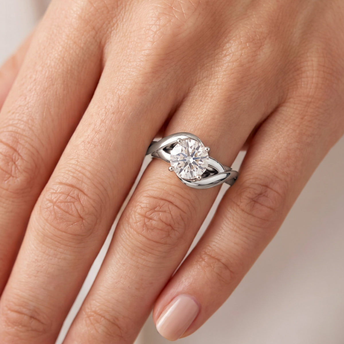 Arlana white gold Celtic knot engagement ring on hand. The round brilliant centre diamond in a four claw setting above the interlaced band. also available in platinum.