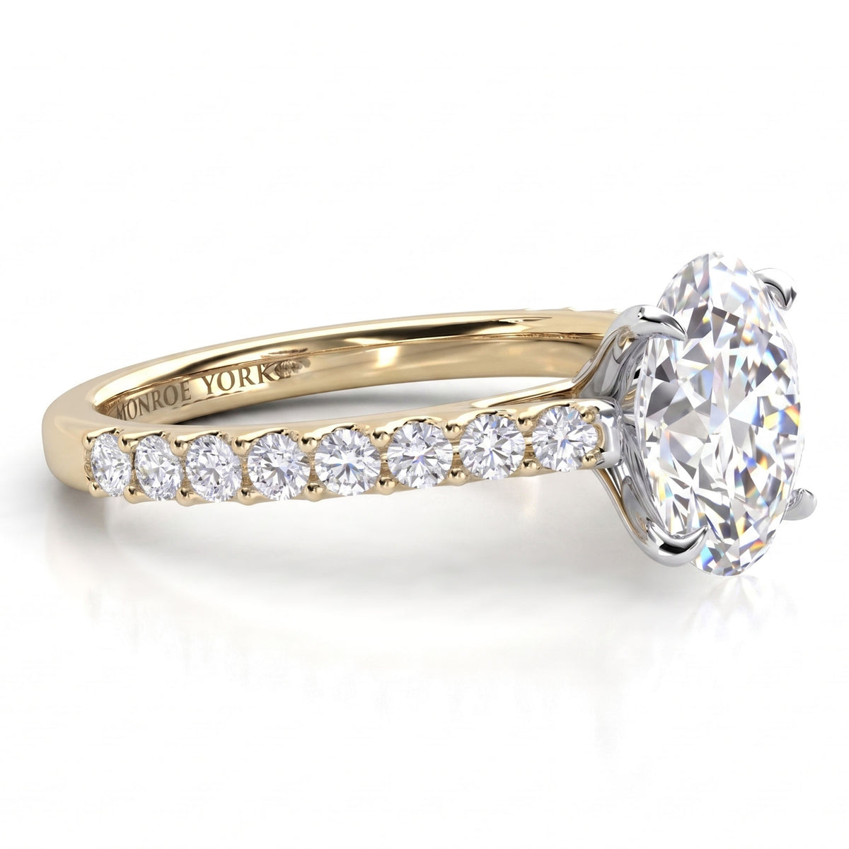 A yellow gold diamond engagement ring with a large oval centre stone and a pavé band featuring smaller round diamonds.