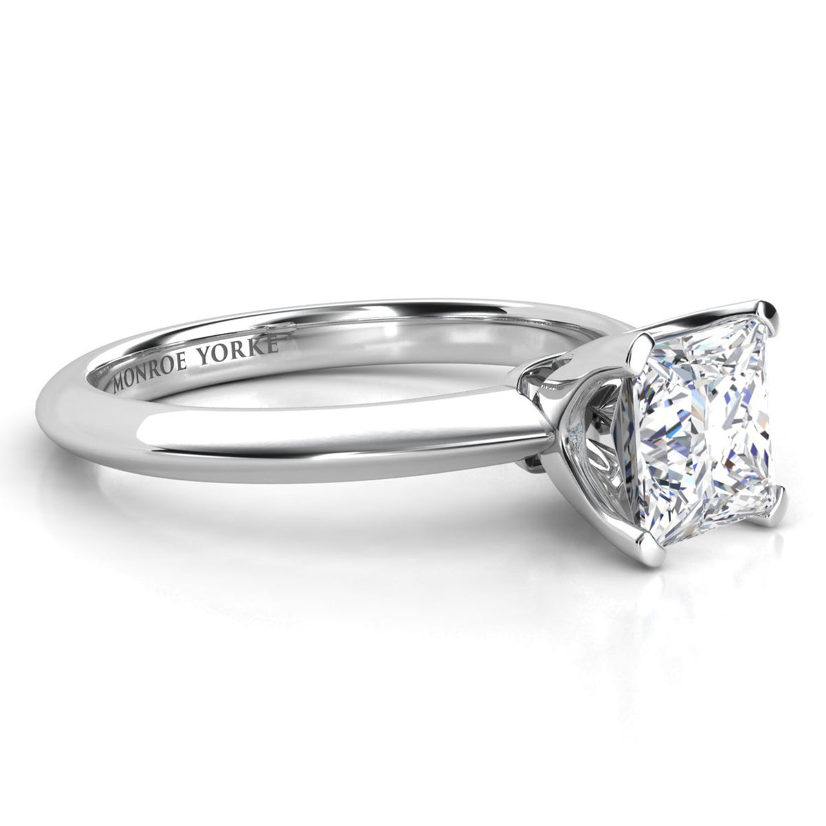 A classic solitaire engagement ring featuring a princess cut diamond set in a polished white gold or platinum band. The brand name 'MONROE YORKE' is engraved on the inner band.