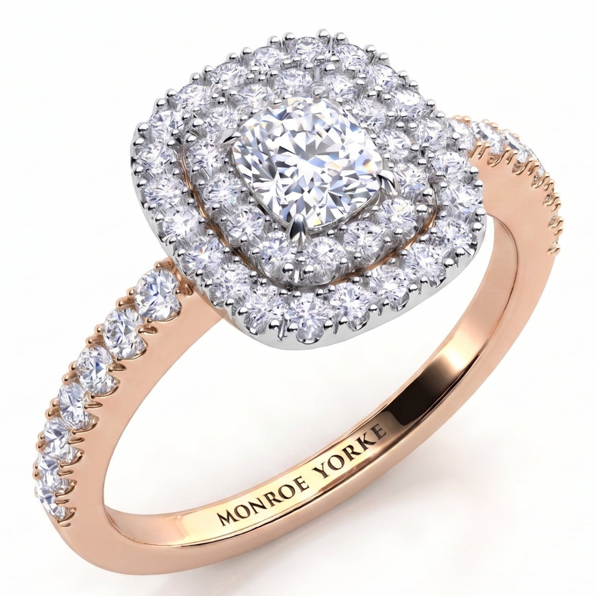 Norah double halo cushion cut engagement ring in rose gold, angled view of the cushion cut centre diamond framed by two diamond halos in a white metal setting head, Monroe Yorke engraved inside the band.