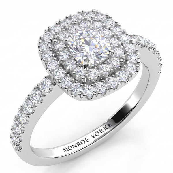 Norah double halo cushion cut engagement ring in white gold or platinum, angled view of the cushion cut centre diamond framed by two diamond halos, with round diamonds claw set down the band.