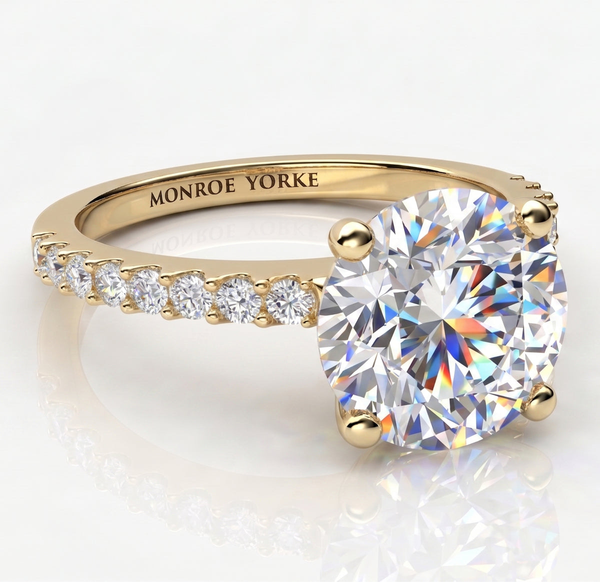 A yellow gold engagement ring with a large round brilliant-cut center stone and a row of smaller diamonds along the band.