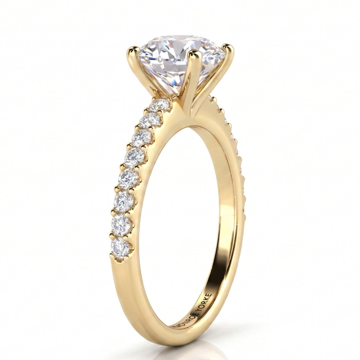 /Side view of Spring - a yellow gold solitaire engagement ring featuring a large round brilliant-cut center stone and a pavé-set row of small clear stones along the shank.