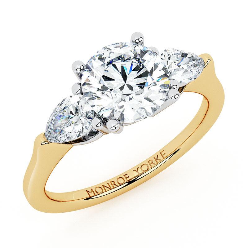 Adele diamond trilogy ring.  Three stone ring.  Centre round brilliant cut diamond and pear shaped diamonds.  Yellow gold.