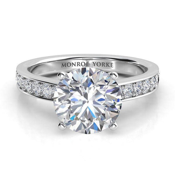 Danae - Platinum Round diamond ring in a 4 claw setting with pave set diamonds on the sweep up band. Front view.