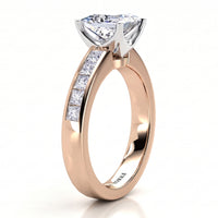 A rose gold engagement ring featuring a large princess cut diamond center stone and a row of smaller princess-cut diamonds on the band, shown on a clean white background.