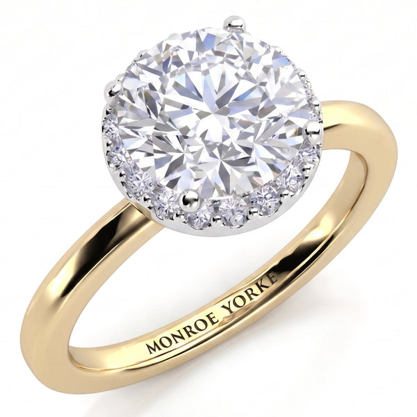 Alexa unique halo engagement ring in yellow gold, angled view of the round brilliant centre diamond with the halo set beneath it, Monroe Yorke engraved on the band.