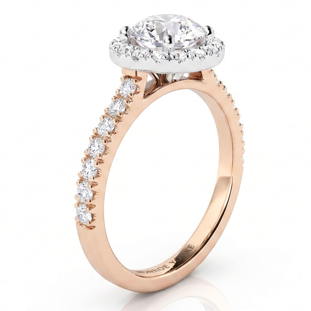 A rose gold engagement ring with a round-cut diamond centre stone in a halo setting and a pavé band featuring a row of smaller round diamonds, shown on a white background.