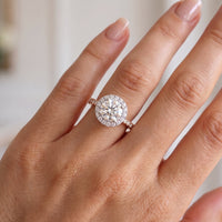 Ariana round diamond halo engagement ring in rose gold shown on a hand. 