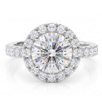 Ariana - a round-cut halo engagement ring featuring a large centre stone surrounded by a halo of smaller stones, with a pavé-set band. White gold or platinum. 