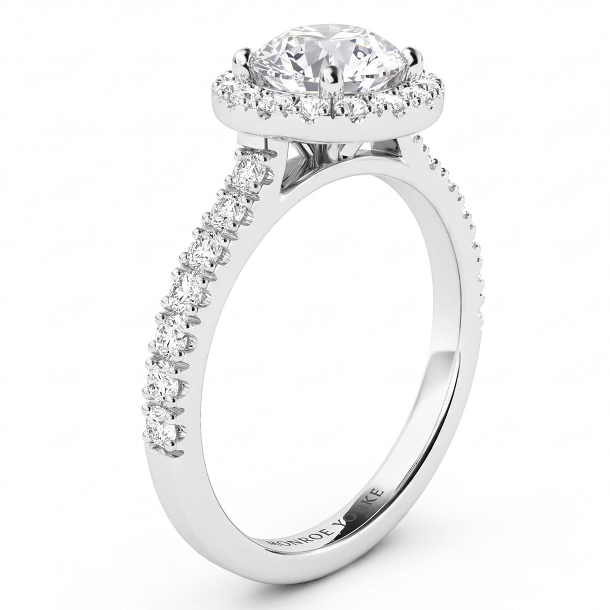 A white gold or platinum halo engagement ring featuring a round-cut centre stone surrounded by a halo of smaller stones, with a pavé-set shank, shown on a white background.