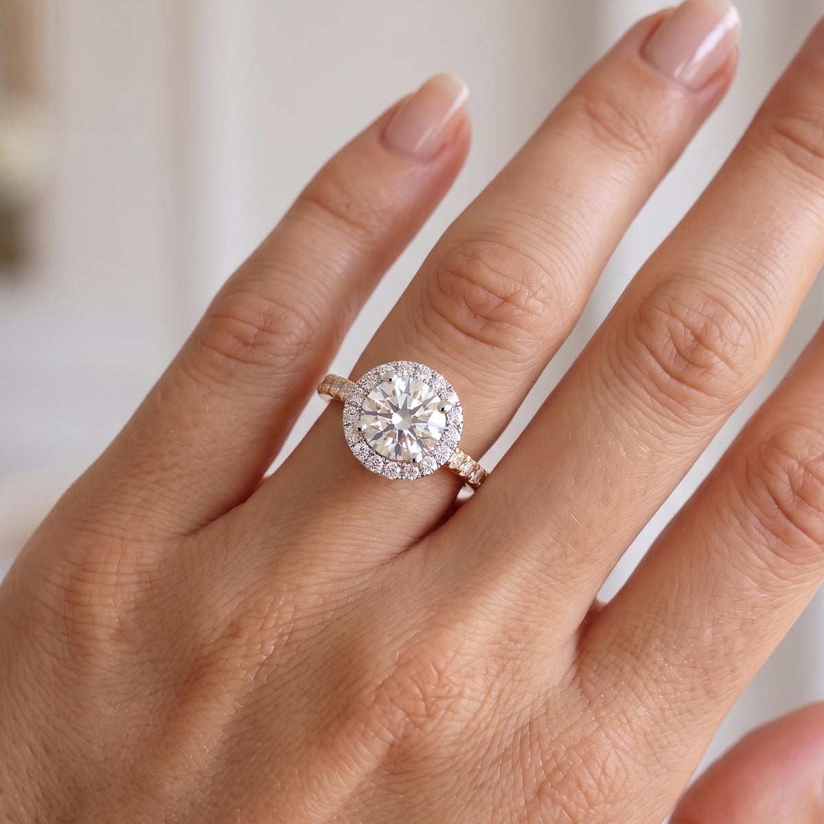 Ariana - round diamond halo engagement ring shown on a hand. Yellow Gold