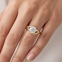 Arlana yellow gold Celtic knot engagement ring on hand. The round brilliant centre diamond in a four claw setting above the interlaced band.