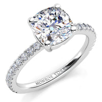White gold or platinum  diamond engagement ring with a cushion-cut center stone and a pavé-set band  on a clean white background.