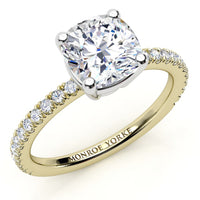 A yellow gold engagement ring featuring a large cushion-cut diamond center stone and a pavé band 