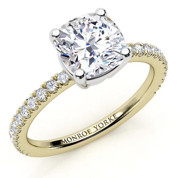 A yellow gold engagement ring featuring a large cushion-cut diamond center stone and a pavé band 