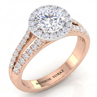 A rose gold halo engagement ring with a round-cut centre stone and smaller accent stones along the split shank, shown on a clean white background. 