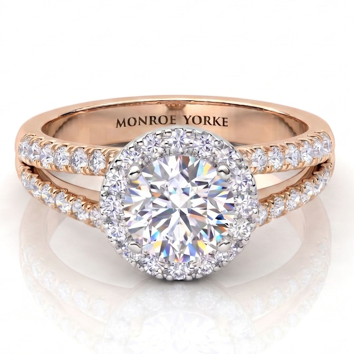 Rose gold halo engagement ring with a round-cut centre diamond and pavé-set diamonds on the band, engraved with 'MONROE YORKE' inside, shown on a white reflective background.