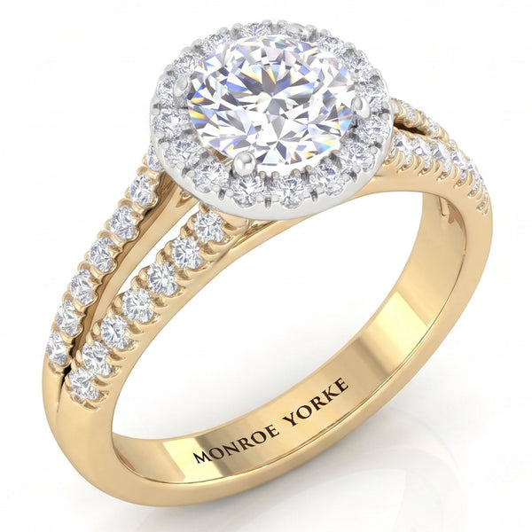 A yellow gold halo engagement ring with a round-cut centre stone and pavé-set accent stones, featuring the engraved brand name 'MONROE YORKE' on the inner band, set against a clean white background.