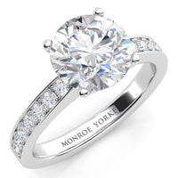Danae engagement ring in white gold or platinum. Round brilliant centre diamond in a four claw setting with pave-set shoulder diamonds. Top view.