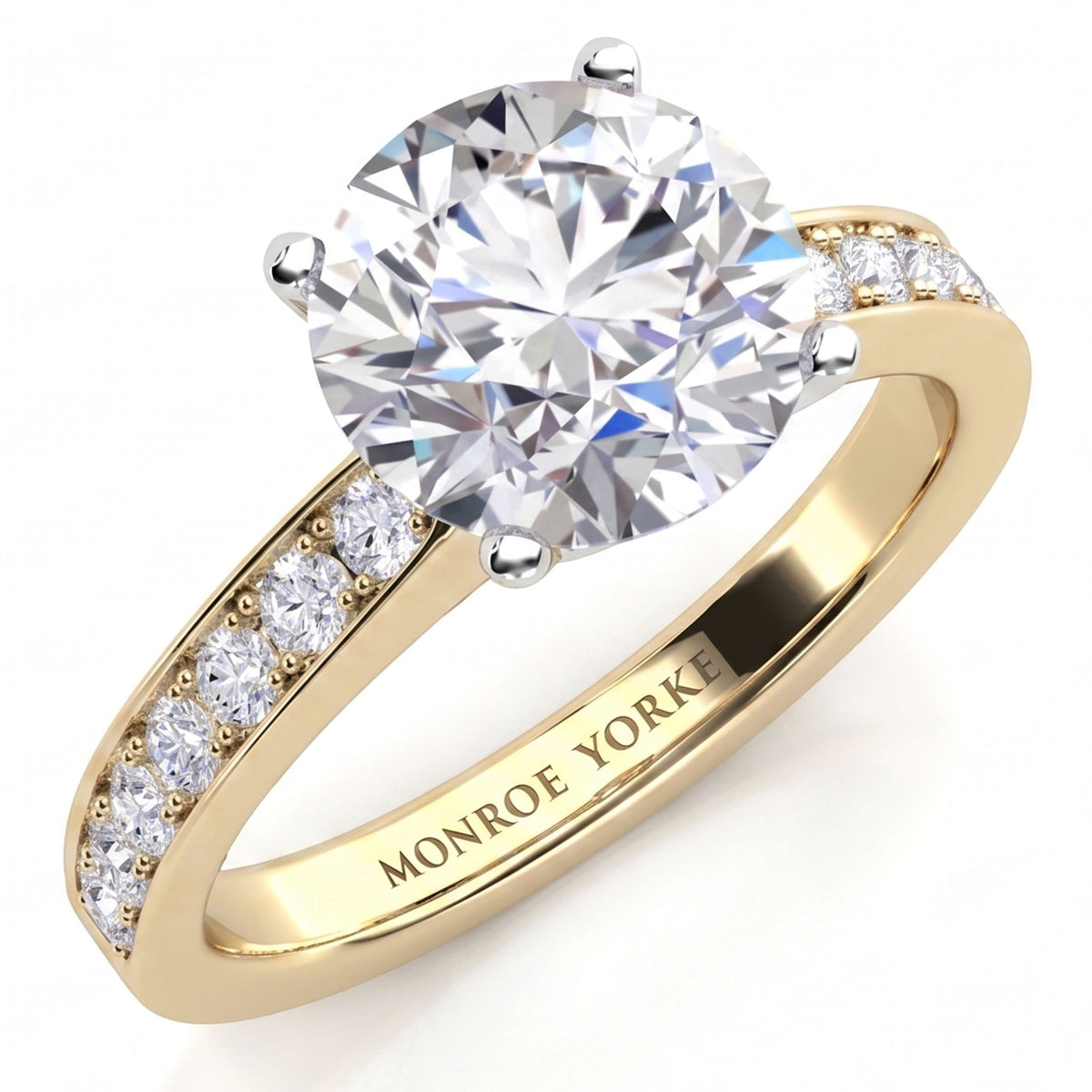 Danae engagement ring in yellow gold. Round brilliant centre diamond in a four claw setting with pave-set shoulder diamonds, MONROE YORKE engraved inside the band.