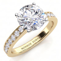 Danae engagement ring in yellow gold. Round brilliant centre diamond in a four claw setting with pave-set shoulder diamonds, MONROE YORKE engraved inside the band.