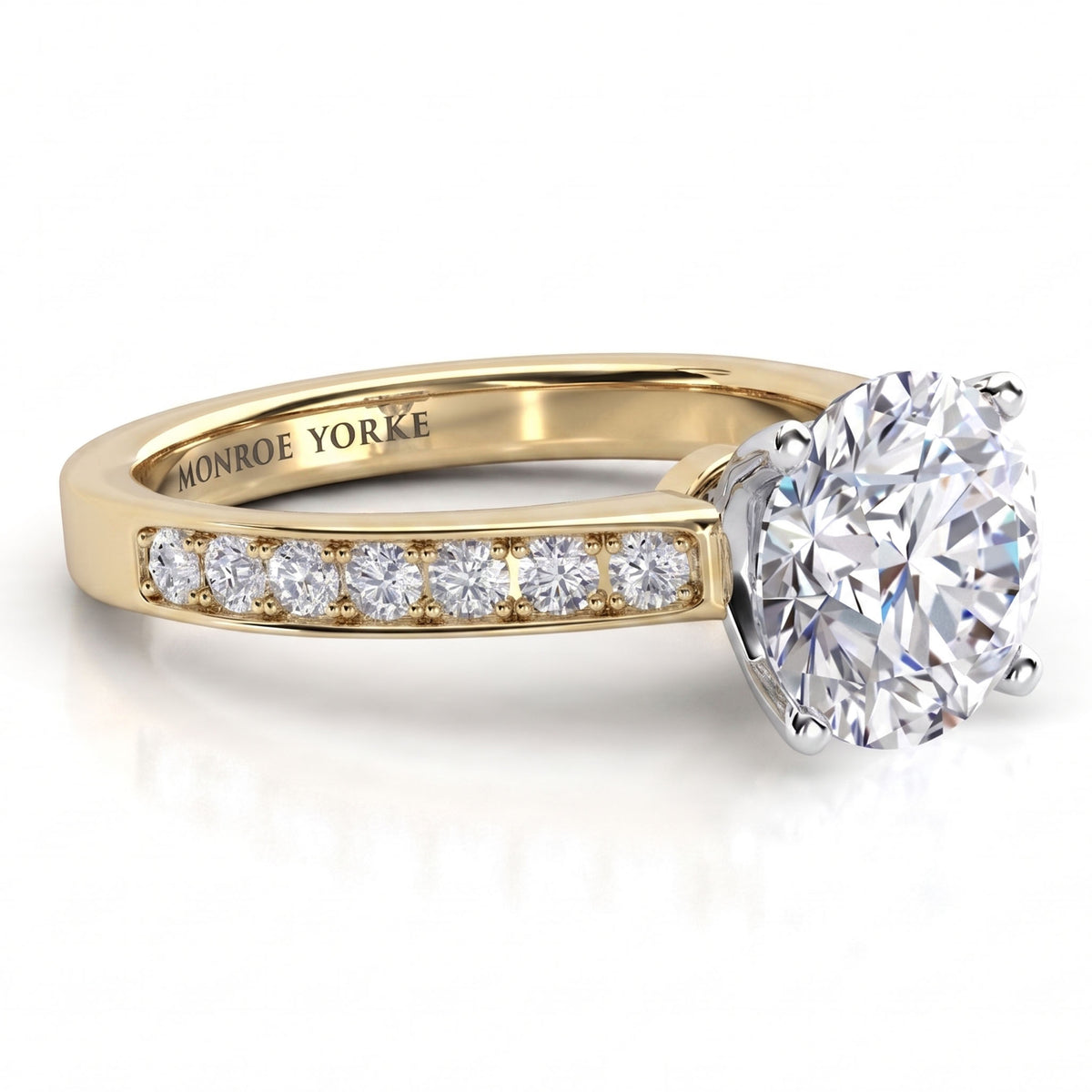 Danae engagement ring in yellow gold. Round brilliant centre diamond above a row of pave-set diamonds.