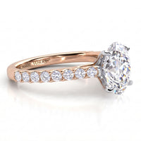 A rose gold engagement ring featuring a large oval-cut center stone and a row of smaller round stones along the band