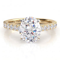 A yellow gold engagement ring featuring a large oval-cut center diamond and a row of small round diamonds on the shoulders, shown on a clean white background.