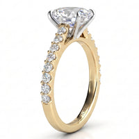 A yellow gold solitaire engagement ring with a large round-cut diamond center stone and a row of smaller diamonds along the shank, shown on a clean white background.