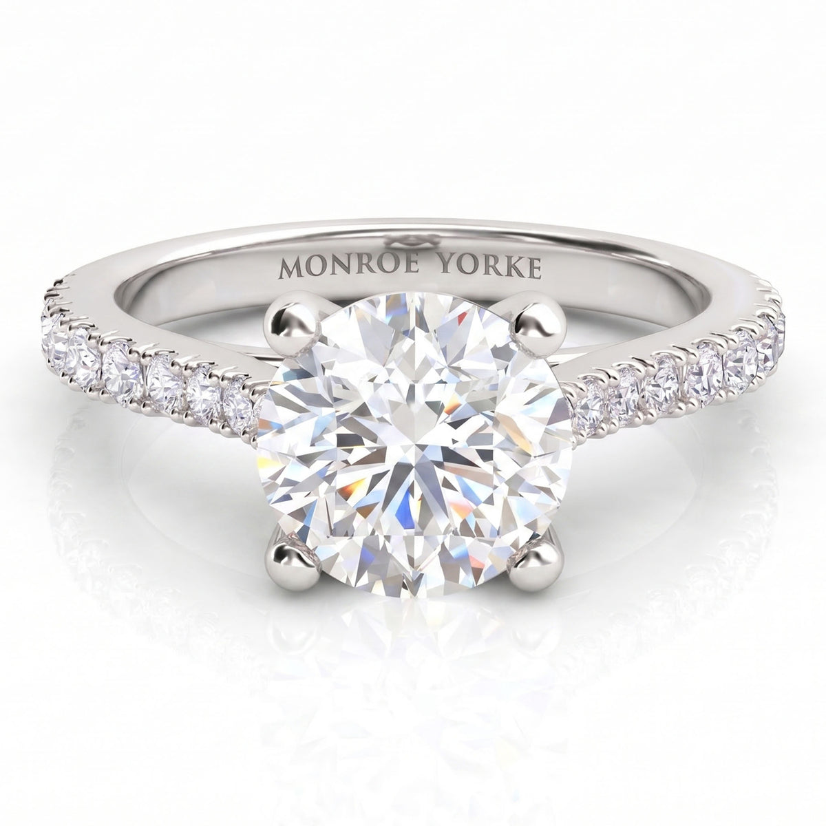 Enya engagement ring in white gold or platinum, round centre diamond in a four claw setting with diamonds on the sweep up band.