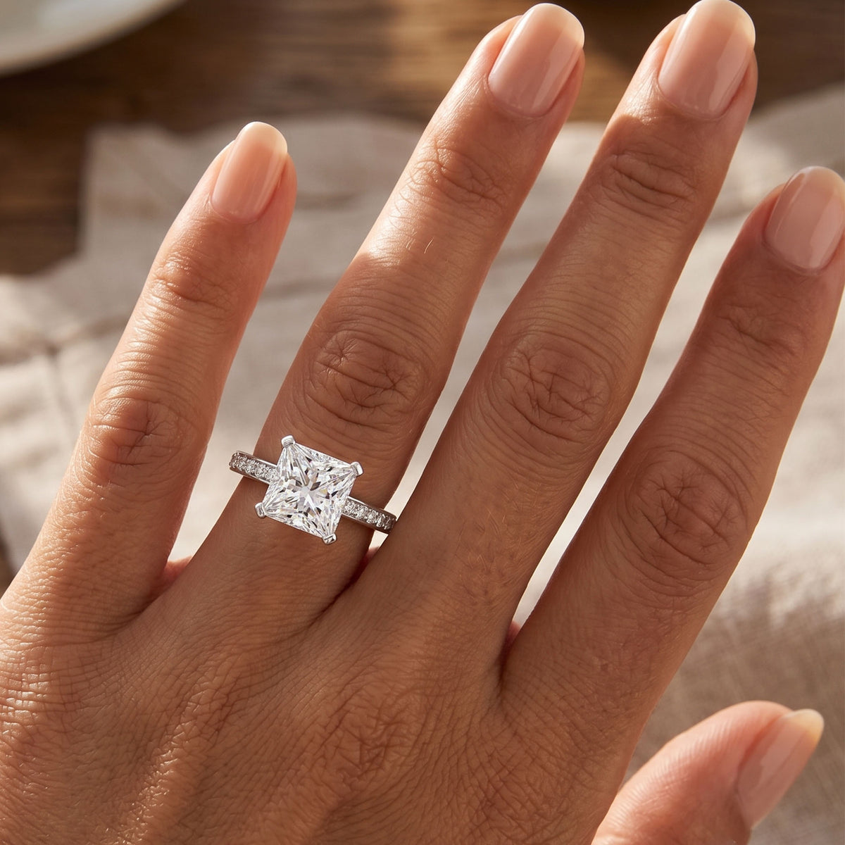 Fifth Avenue engagement ring in white gold or platinum, princess cut centre diamond, shown worn on a hand.