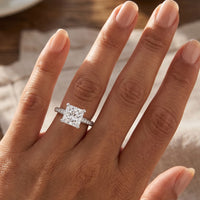 Fifth Avenue engagement ring in white gold or platinum, princess cut centre diamond, shown worn on a hand.