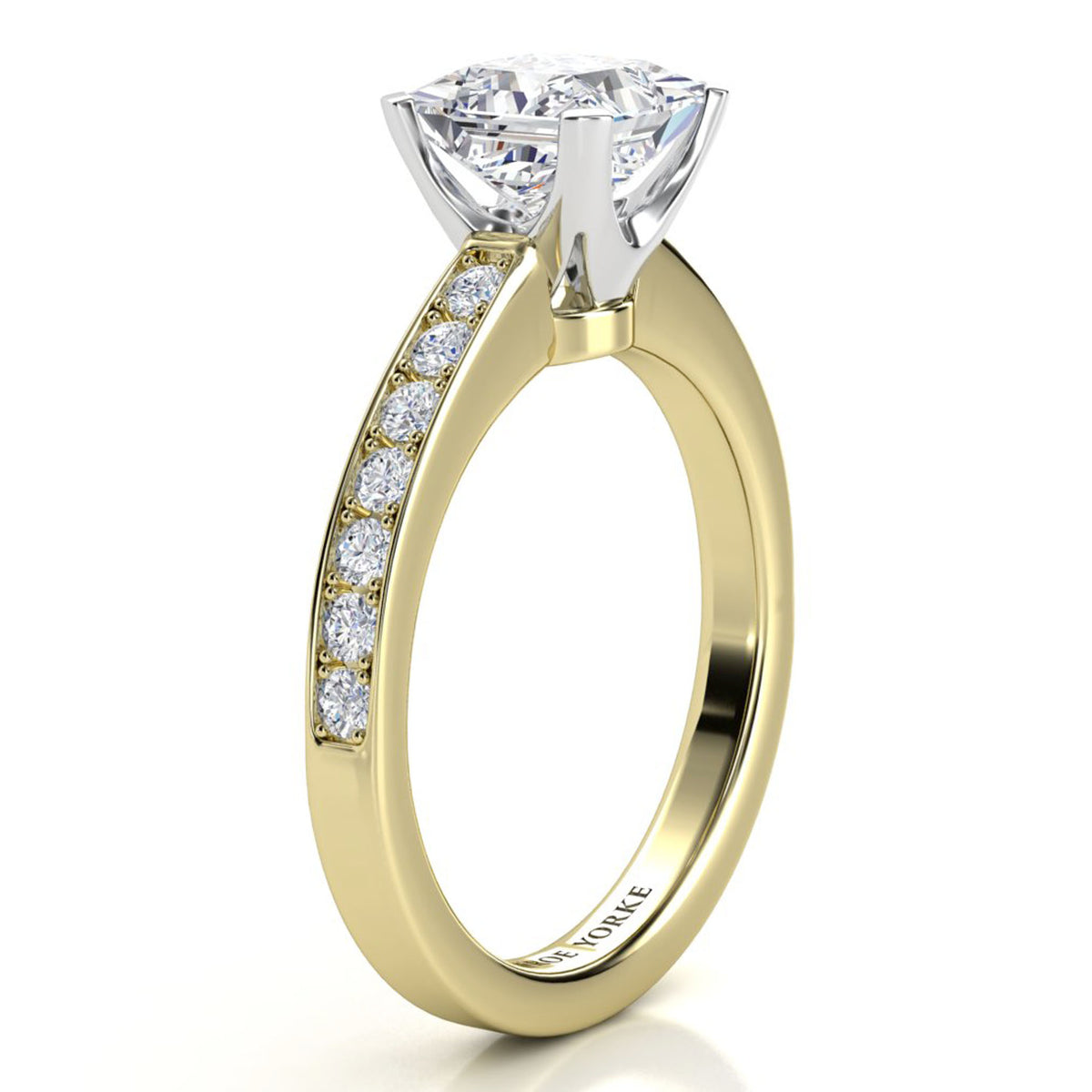 Fifth Avenue yellow gold engagement ring, close view of the princess cut centre diamond and the micro claw set band.