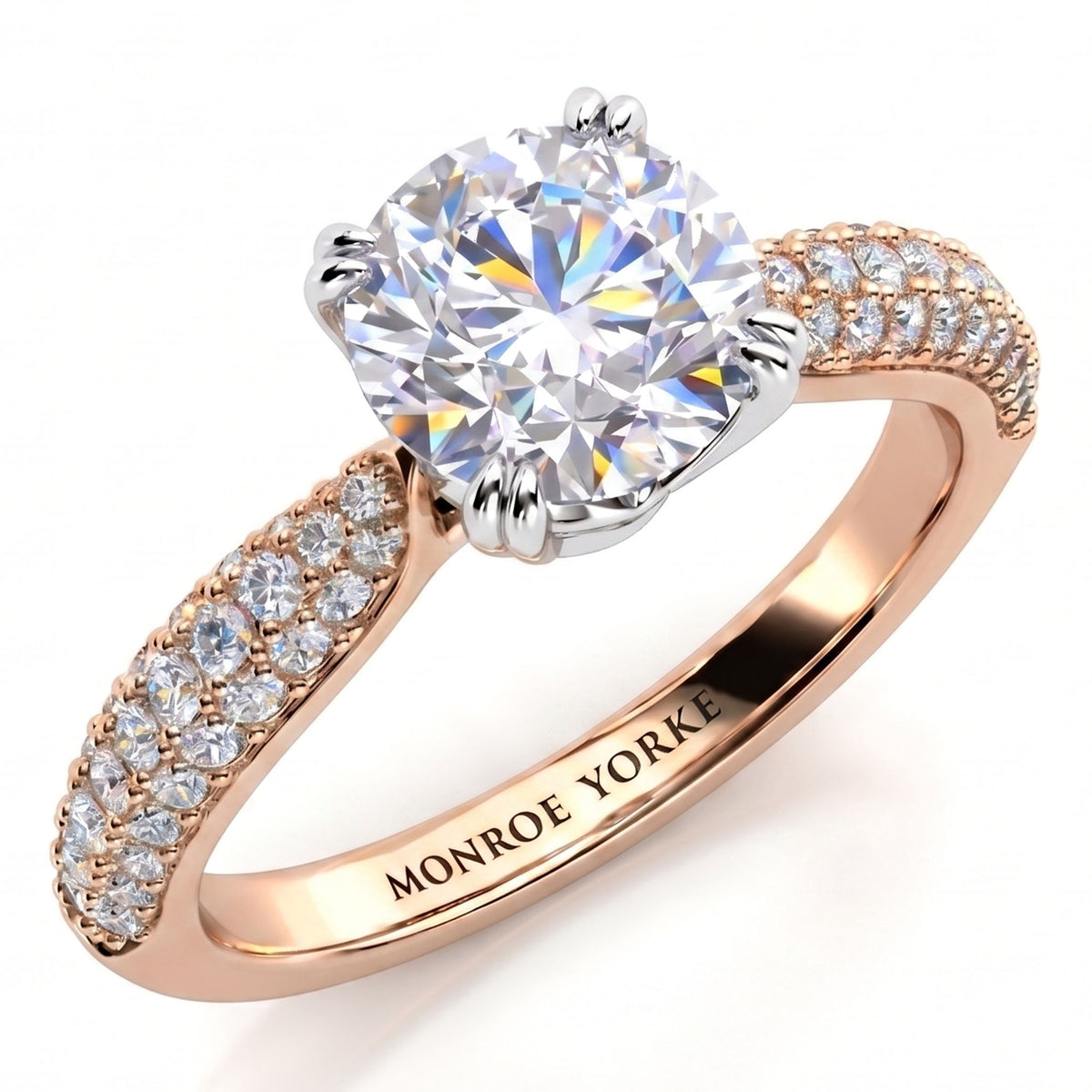 A close-up studio shot of a ring on a white background. The Harper diamond engagement ring features a large round brilliant-cut center stone in a silver-toned setting, with a rose gold band decorated with pavé-set clear stones on the shoulders.