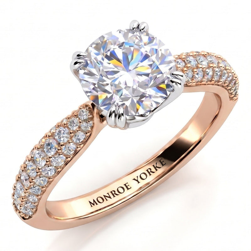 A close-up studio shot of a ring on a white background. The Harper diamond engagement ring features a large round brilliant-cut centre stone in a silver-toned setting, with a rose gold band decorated with pavé-set clear stones on the shoulders.