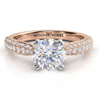 A rose gold diamond ring with a round-cut center stone and pavé-set diamonds along the shoulders.