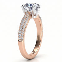 A rose gold engagement ring featuring a large round-cut clear center stone in a four-prong setting, with pavé-set clear stones along the shank. The ring is shown on a clean white background.