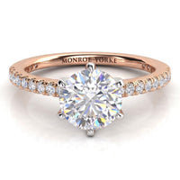 A rose gold solitaire engagement ring with a round brilliant-cut center diamond and small pavé diamonds on the band.