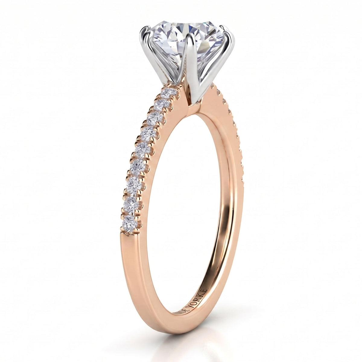 A rose gold solitaire engagement ring with a round-cut diamond center stone and a pavé diamond band, shown on a clean white background.