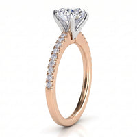 A rose gold solitaire engagement ring with a round-cut diamond center stone and a pavé diamond band, shown on a clean white background.