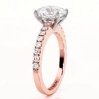 A rose gold solitaire engagement ring with aoval-cut diamond center stone and a pavé band of smaller round diamonds.