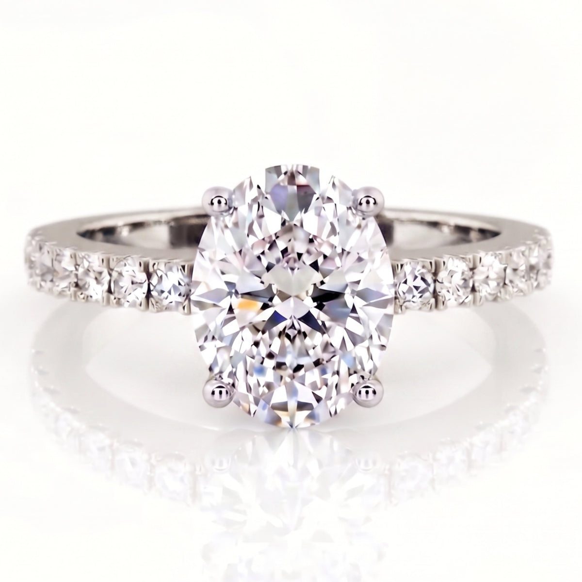 An oval-cut diamond engagement ring with a white gold or platinum band set with small round diamonds,