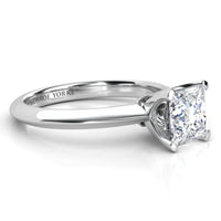 A classic solitaire engagement ring featuring a princess cut diamond set in a polished white gold or platinum band. The brand name 'MONROE YORKE' is engraved on the inner band.