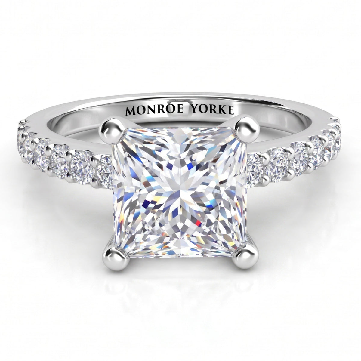 Lutèce engagement ring in white gold or platinum, front view of the princess cut centre diamond with a row of small round diamonds down each shoulder.