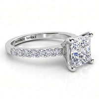 Lutèce engagement ring in white gold or platinum, low side view showing the princess cut centre diamond and the diamond set shoulders.