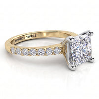 Lutèce yellow gold engagement ring, low side view showing the princess cut centre diamond and the diamond set shoulders.