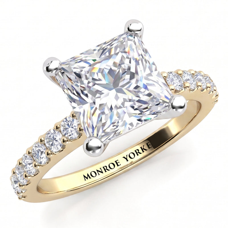Lutèce yellow gold engagement ring, angled view of the princess cut centre diamond in a four claw setting with micro claw set diamonds along the shoulders, Monroe Yorke engraved on the band.